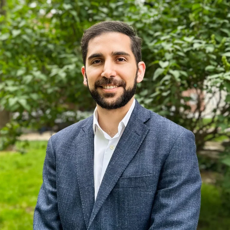 Headshot of Michael Karamardian on an outdoor background with a tree behind him.